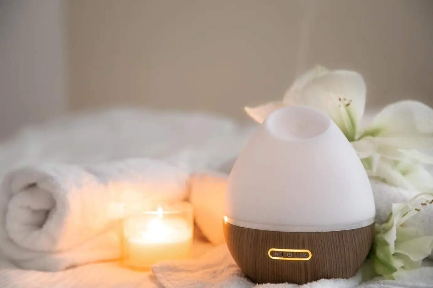 Gemütliches Spa-Arrangement mit Aromadiffusor, Kerze und Blumen