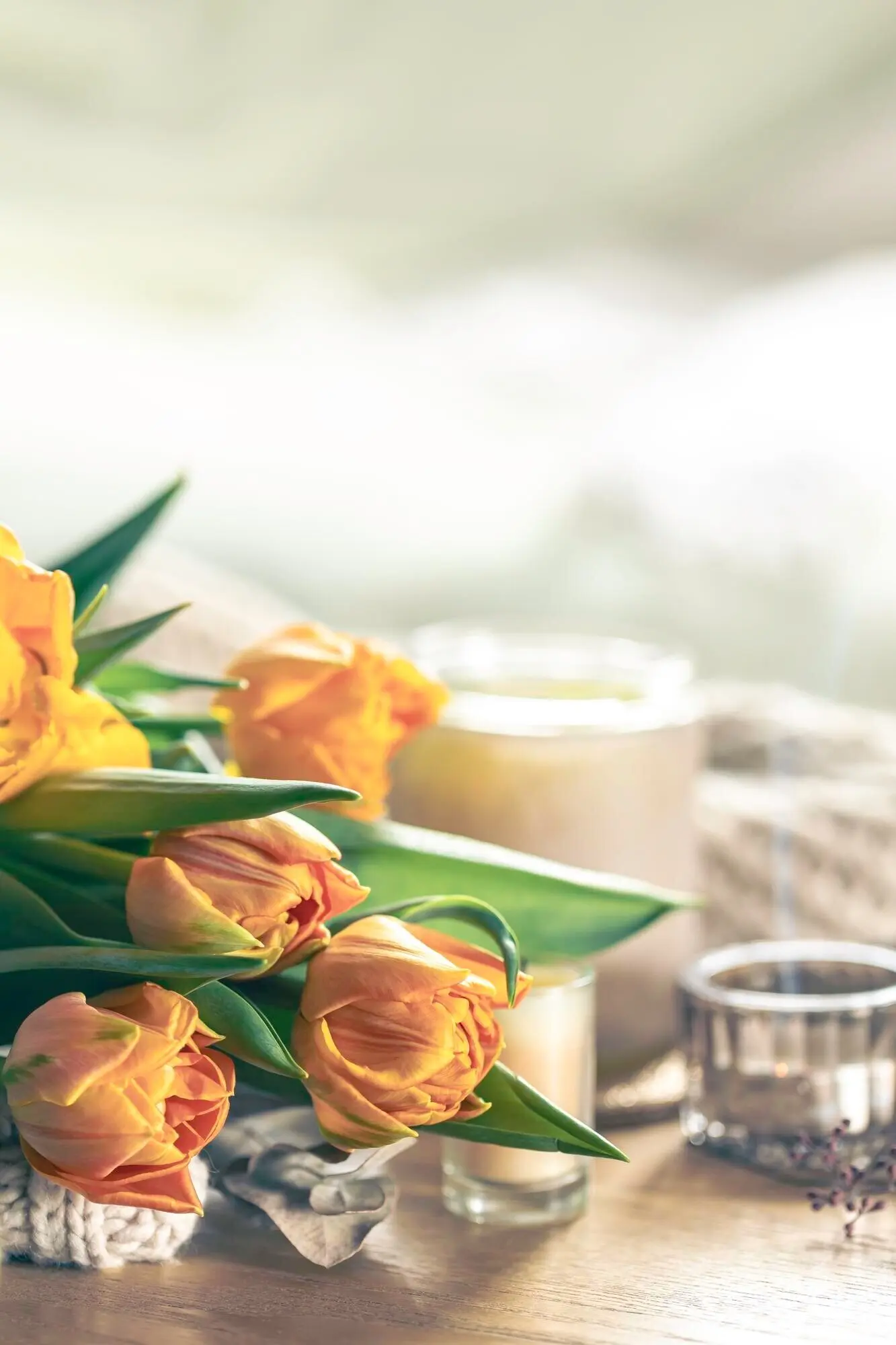 Frühlingshintergrund mit gelben Tulpen, Kerzen und einem gestrickten Element.